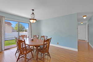 Dining room featuring baseboards, a textured ceiling, and light wood-style flooring