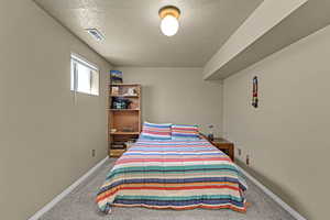 Bedroom with baseboards, carpet, a textured ceiling, and visible vents