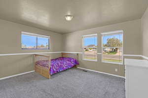 Carpeted bedroom featuring a textured ceiling, visible vents, and baseboards