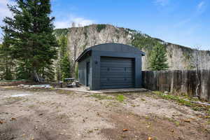 Detached garage with fence, a view of trees, and a mountain view