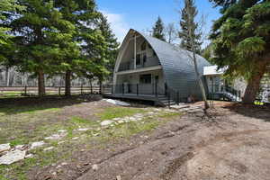 Exterior space featuring fence, a gambrel roof, and a balcony