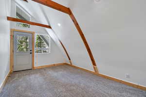 Entrance foyer featuring baseboards, lofted ceiling with beams, and carpet flooring