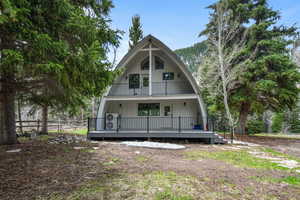 Back of house with fence and a gambrel roof