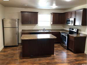 Kitchen featuring a sink, a kitchen island, stainless steel appliances, and dark brown cabinets
