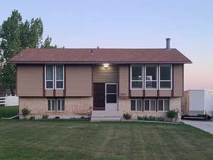 View of front of property featuring brick siding, a front lawn, and partial fence