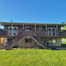 Back of property with large covered deck and double stairs to backyard and spot for future hot tub