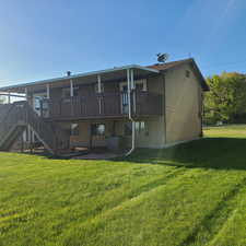 Back of property with a yard, large covered deck, and double stairs