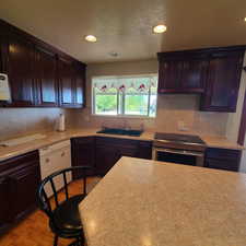 Kitchen with backsplash, light wood-type flooring, a sink, light countertops, and electric stove