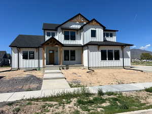 Modern inspired farmhouse featuring a shingled roof, board and batten siding, and a mountain view