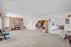 Carpeted living area featuring a stone fireplace and visible vents