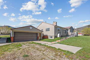 View of front of home featuring driveway, a chimney, a front yard, an outbuilding, and a garage