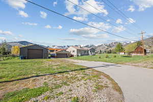 View of front of property featuring driveway, fence, a mountain view, and a front lawn