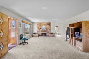 Carpeted living area with a stone fireplace and visible vents