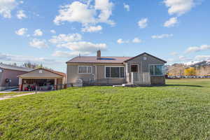 Rear view of property with a garage, fence, a chimney, a lawn, and a mountain view