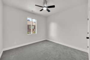 Carpeted empty room featuring a ceiling fan and baseboards