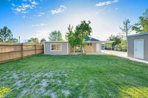 Rear view of property featuring a yard, fence, and a patio area