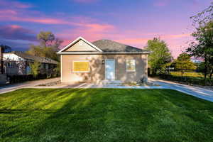 View of front of home with a yard, fence, and roof with shingles