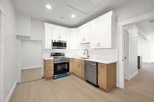 Kitchen featuring decorative backsplash, visible vents, appliances with stainless steel finishes, a sink, and light wood finished floors