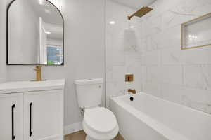 Full bath featuring visible vents, vanity, toilet, baseboards, and shower / tub combination