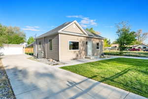 Bungalow-style home with an outdoor structure, central air condition unit, a front yard, and fence
