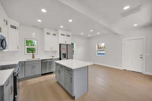 Kitchen featuring visible vents, light wood-style floors, appliances with stainless steel finishes, and gray cabinetry
