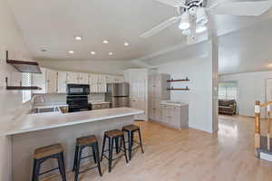 Kitchen featuring open shelves, a sink, a peninsula, and black appliances