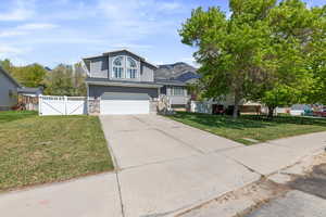 View of front of home featuring fence, an attached garage, a front yard, a gate, and concrete driveway