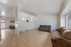 Living room with visible vents, ceiling fan, and wood finished floors
