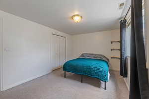 Carpeted bedroom with visible vents, baseboards, and a closet