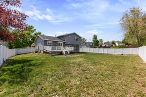 Exterior space with a fenced backyard, a wooden deck, and a lawn