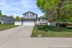 View of front of home featuring concrete driveway, an attached garage, and a front lawn