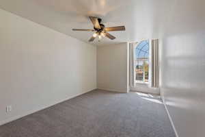 Carpeted spare room with baseboards and ceiling fan