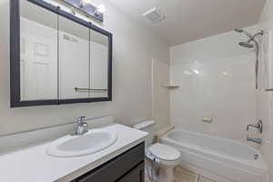 Bathroom featuring vanity, shower / bathtub combination, toilet, and visible vents