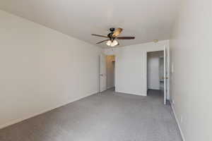Unfurnished bedroom featuring baseboards, ceiling fan, and light colored carpet