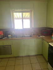 Kitchen featuring a sink, light countertops, plenty of natural light, and light tile patterned flooring