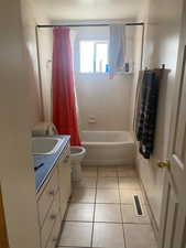 Full bath featuring visible vents, tile patterned flooring, vanity, toilet, and shower / bath combo with shower curtain