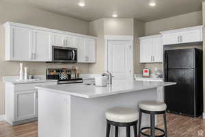 Kitchen featuring stainless steel appliances, white cabinetry, a sink, and light wood-style flooring