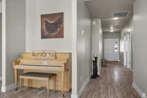 Hall featuring visible vents, baseboards, and wood finished floors