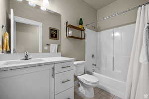 Full bathroom with vanity, visible vents, toilet, baseboards, and shower / bath combo
