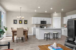 Kitchen featuring a kitchen breakfast bar, light countertops, white cabinets, a chandelier, and stainless steel appliances