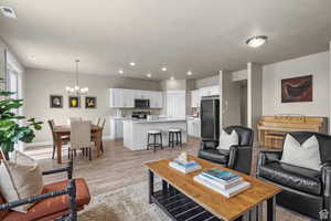 Living room featuring an inviting chandelier, recessed lighting, baseboards, light wood-type flooring, and visible vents