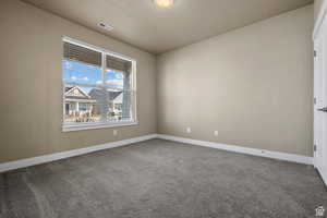 Carpeted spare room featuring visible vents and baseboards