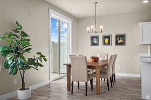 Dining space with baseboards, a chandelier, and wood finished floors