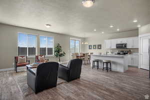 Living area with baseboards, dark wood-style floors, recessed lighting, a textured ceiling, and a notable chandelier