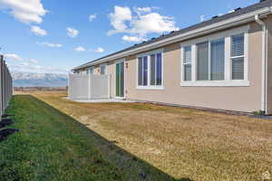 Back of property featuring a lawn, fence, and stucco siding