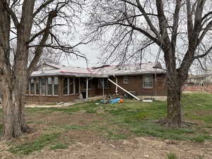 Back of house with brick siding and a sunroom