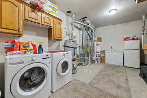 Washroom featuring strapped water heater, cabinet space, water heater, separate washer and dryer, and heating unit