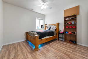 Bedroom with visible vents, light wood-style flooring, and baseboards