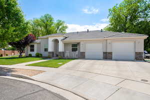 Ranch-style home with driveway, a tile roof, a garage, a front lawn, and stone siding
