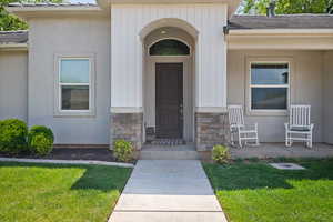 Property entrance featuring a yard, stone siding, and stucco siding